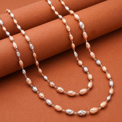 A beaded necklace with alternating faceted rose gold and silver beads, draped elegantly over a textured brown background.