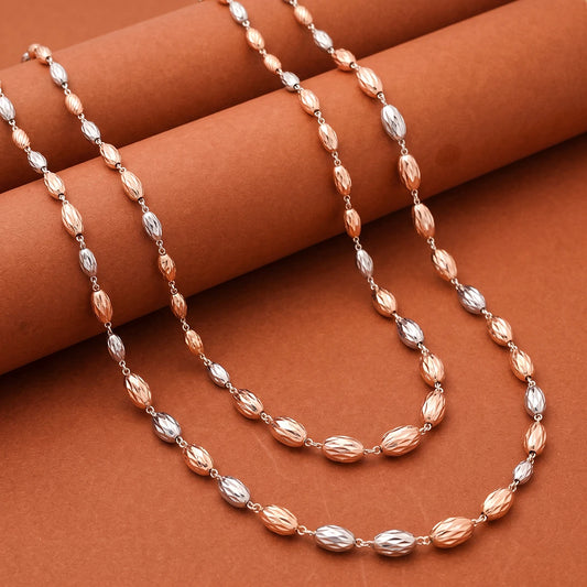A beaded necklace with alternating faceted rose gold and silver beads, draped elegantly over a textured brown background.